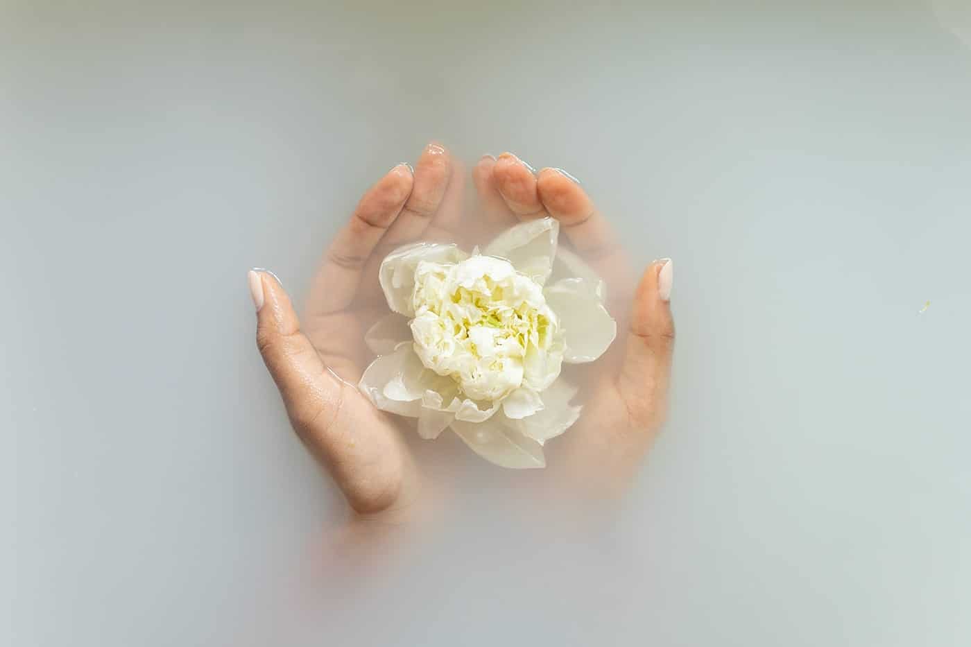 Mejora el aroma de tus jabones hechos en casa con estas opciones de fragancias 3 Unas manos con una flor en el baño con jabones hechos en casa con estas opciones de fragancias.